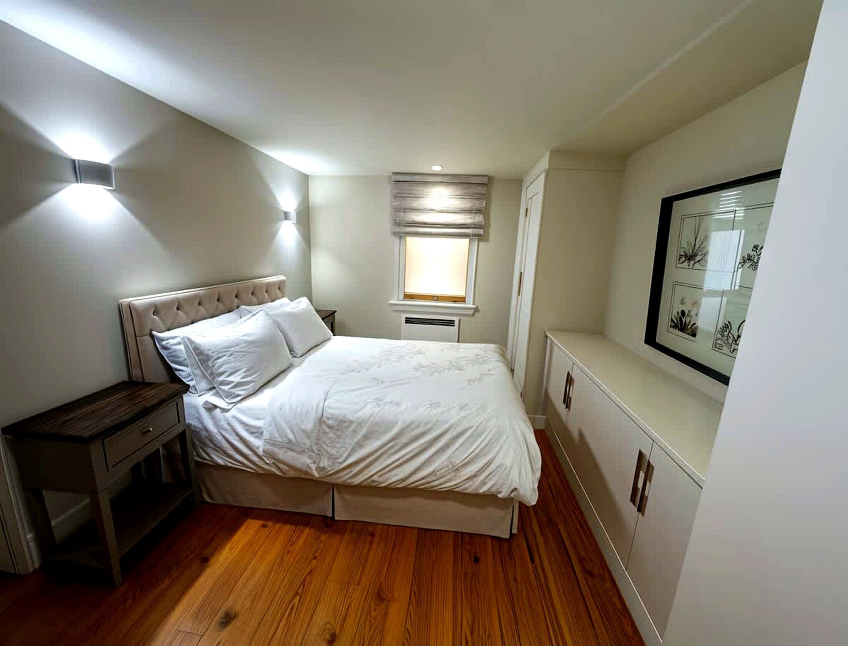 Quarto com cama, mesa de cabeceira, guarda-roupa e janela com persianas.