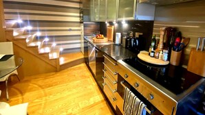 Une cuisine moderne dotée d’appareils électroménagers en acier inoxydable, de meubles en bois et d’un escalier en verre.