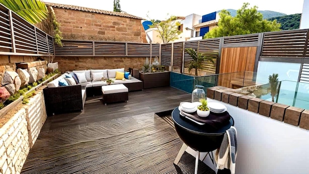 Une terrasse sur le toit, avec un espace salon, une petite table agrémentée d’un vase et une vue sur le paysage urbain.