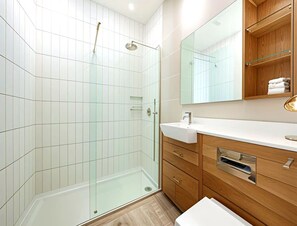 Ein modernes Badezimmer mit einer Duschkabine aus Glas, einem Holzbadezimmer-Möbelstück mit Waschbecken und einem Spiegel darüber.