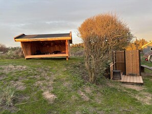 A wooden structure with a sloped roof, a small tree, and a wooden deck. - 4 Star Holiday Home in Lokken (Lokken)