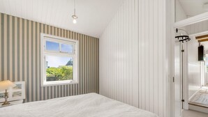 A bedroom with a bed, a window with a view, a bedside table, and a lamp. - 4 Star Holiday Home in Lokken (Lokken)