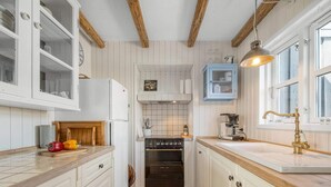 A kitchen with white cabinets, a wooden countertop, a built-in oven, and a hanging light fixture. - 4 Star Holiday Home in Lokken (Lokken)