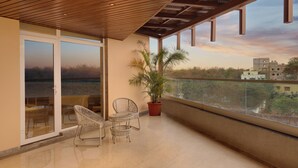 A balcony with a wooden ceiling, a potted plant, and wicker chairs. - Lemon Tree Hotel Bhubaneswar (Bhubaneshwar)