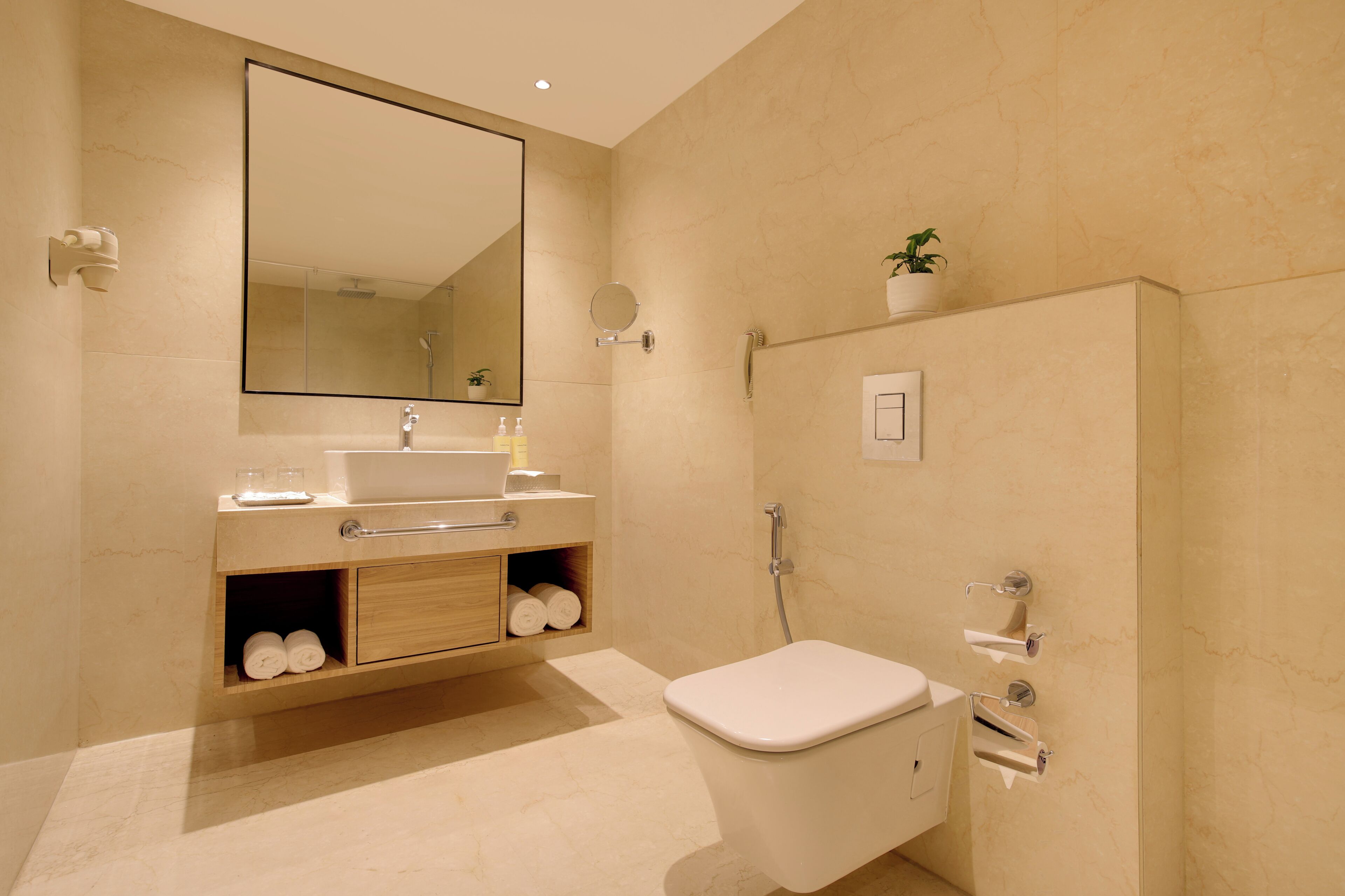 A modern bathroom with a large mirror, a toilet, a sink, and a shower.