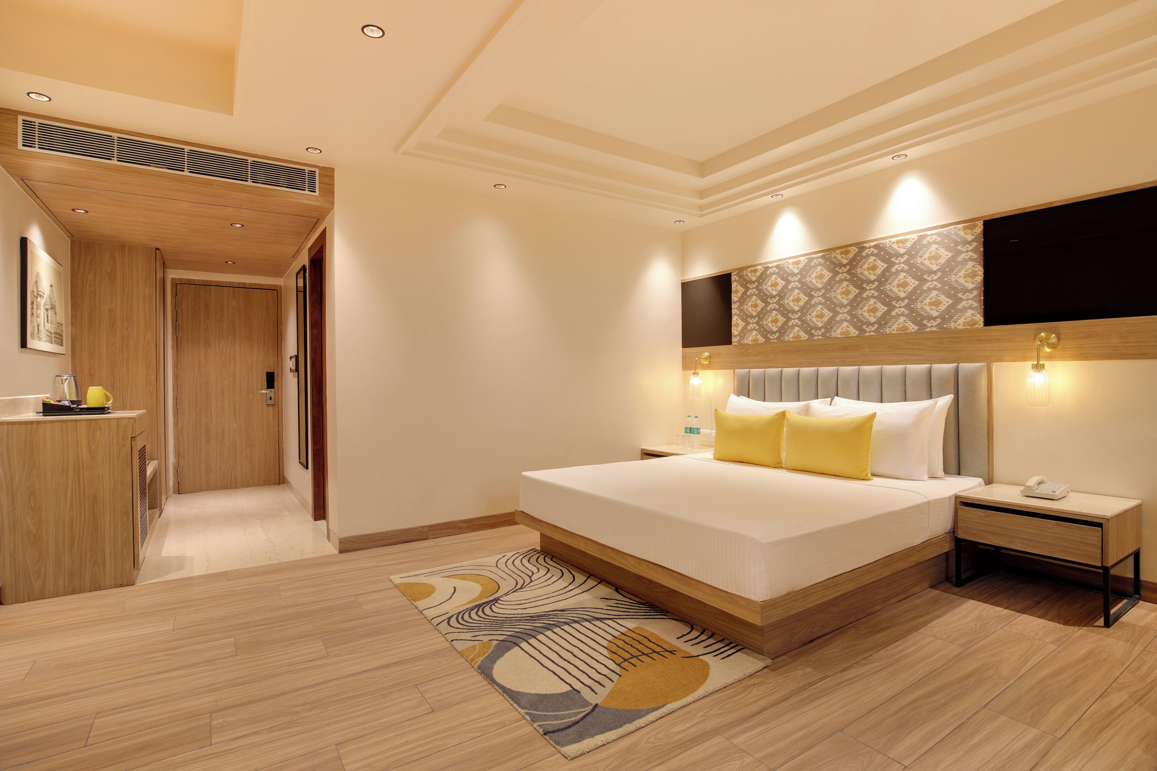 Una habitación de hotel moderna con una cama grande, una mesita de noche y una televisión empotrada.