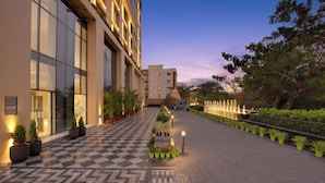 A hotel entrance with a checkered floor, potted plants, and a water feature. - Lemon Tree Hotel Bhubaneswar (Bhubaneshwar)