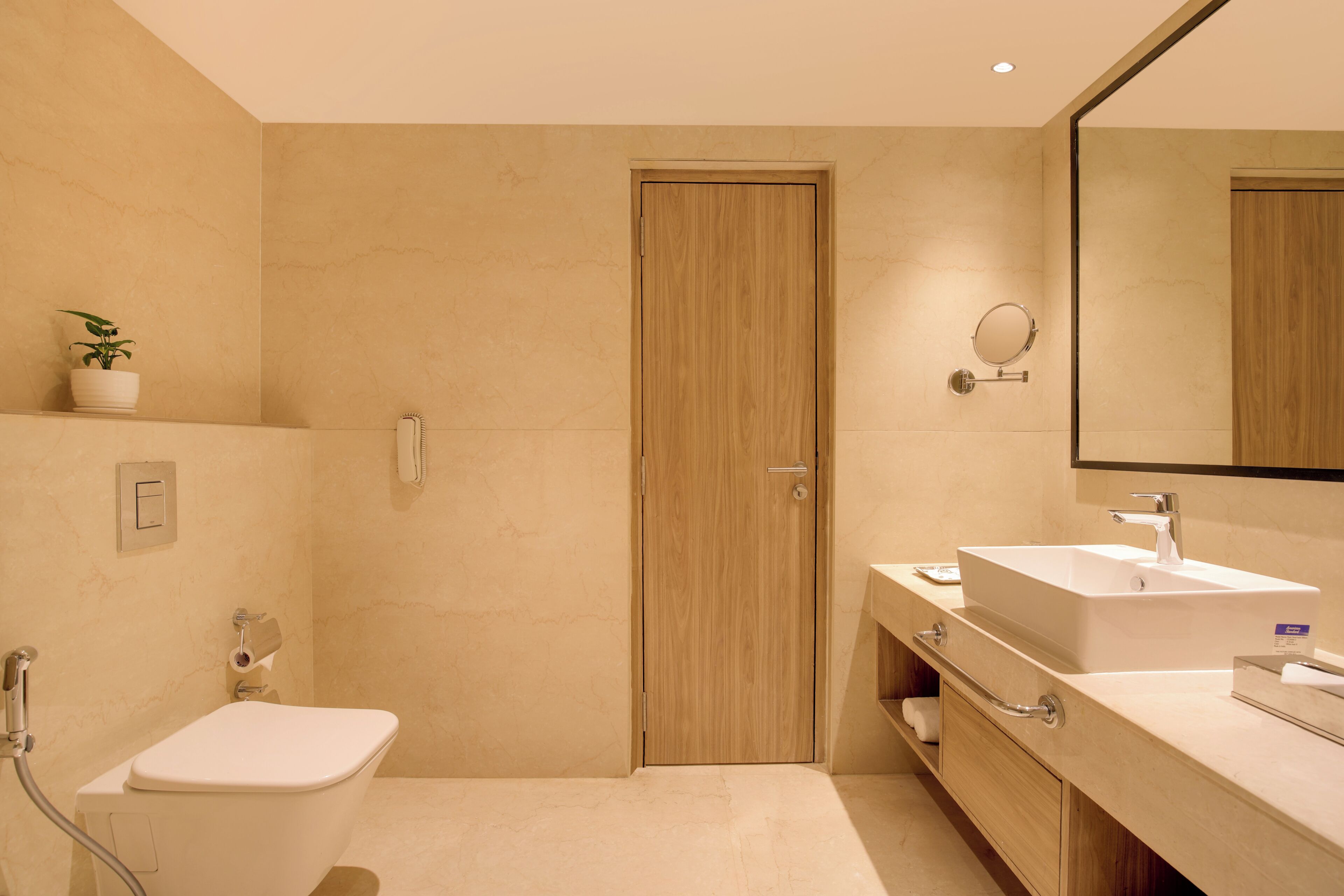 Un baño moderno con puerta de madera, un lavabo blanco, un espejo y una ducha.