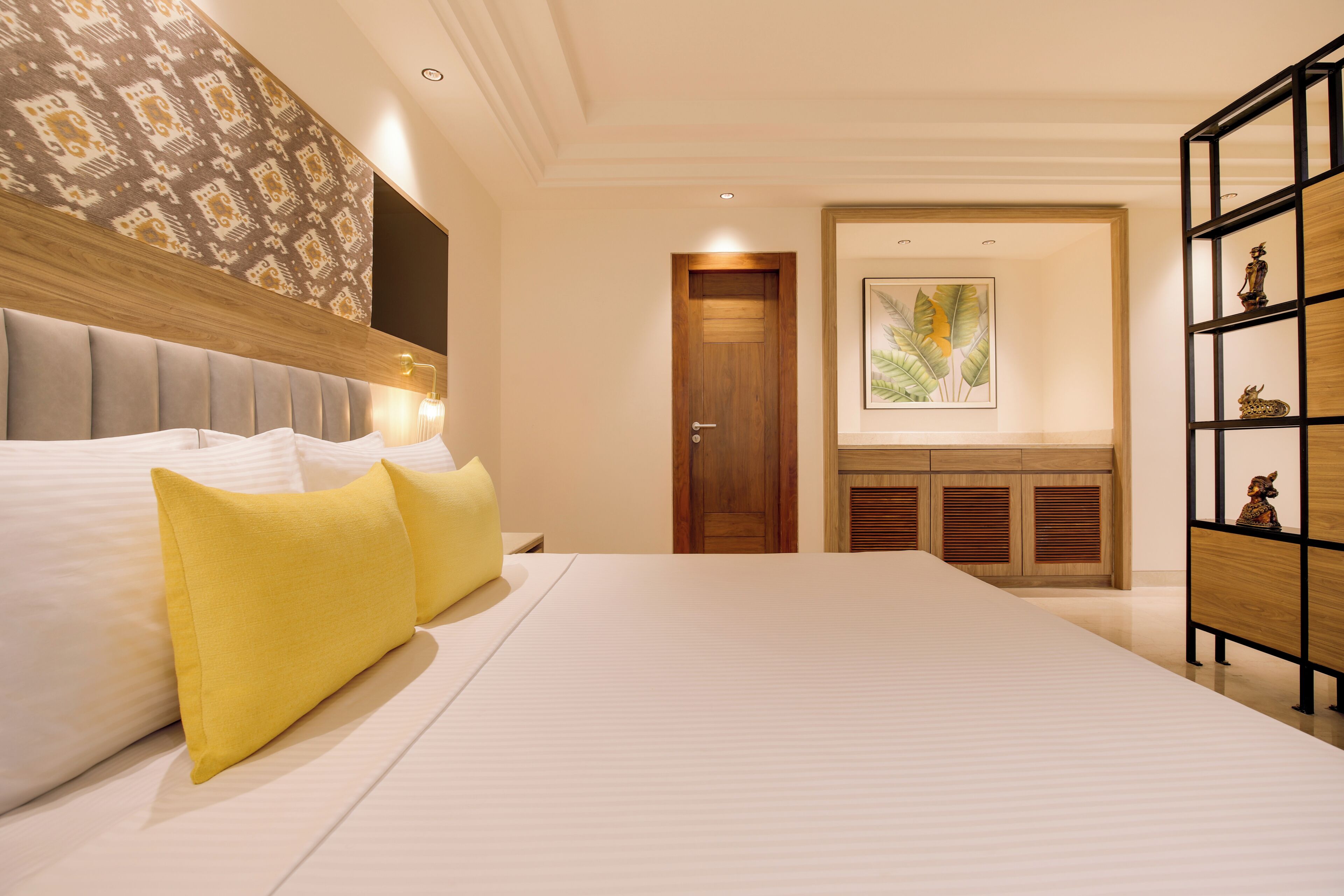 A hotel room with a large bed, a wooden headboard, a wardrobe, and a framed picture on the wall.