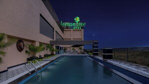 A modern hotel with a swimming pool, a lion head sculpture, and a night sky. - Lemon Tree Hotel Bhubaneswar (Bhubaneshwar)