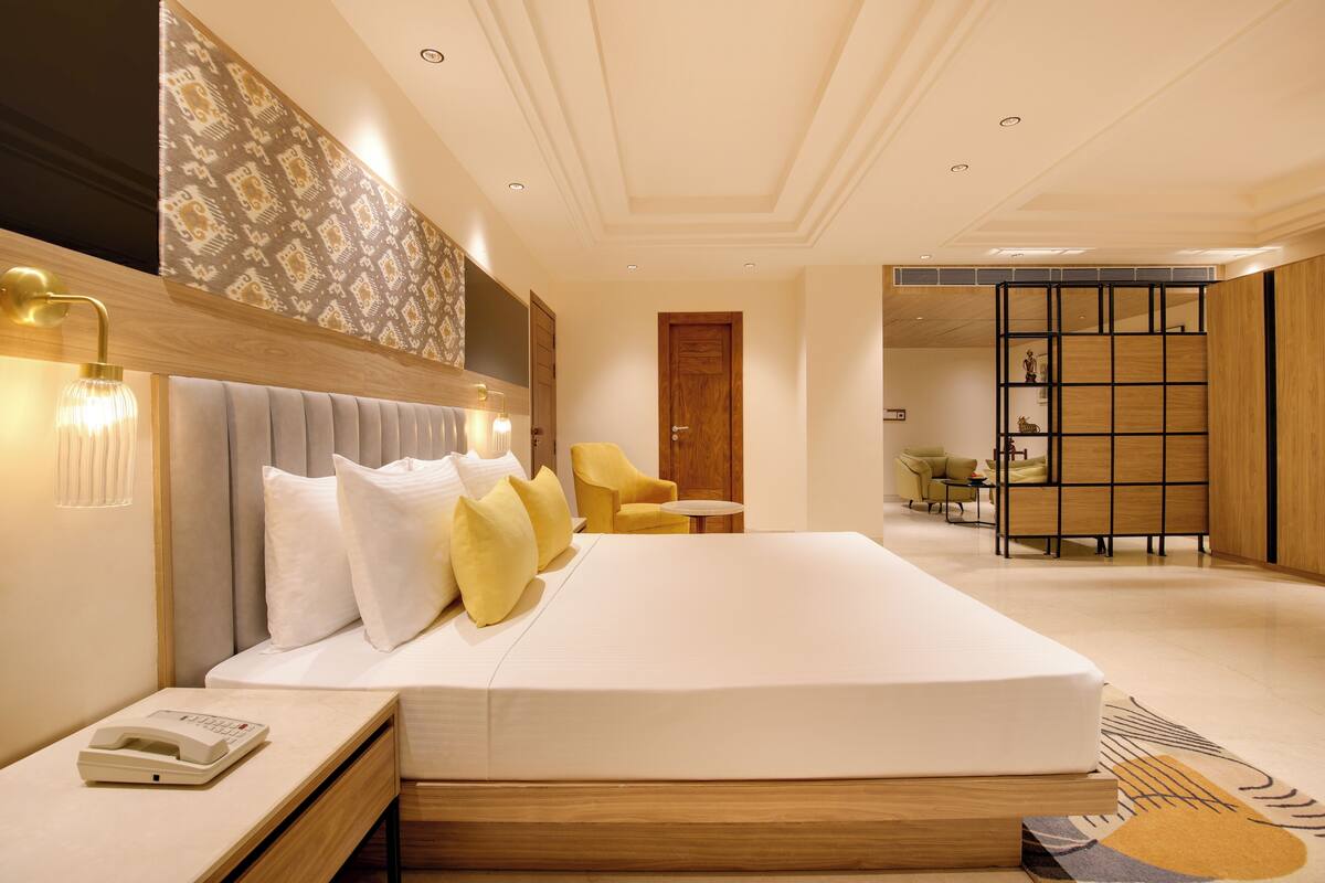 A modern hotel room with a large bed, bedside table, and a small table with chairs.