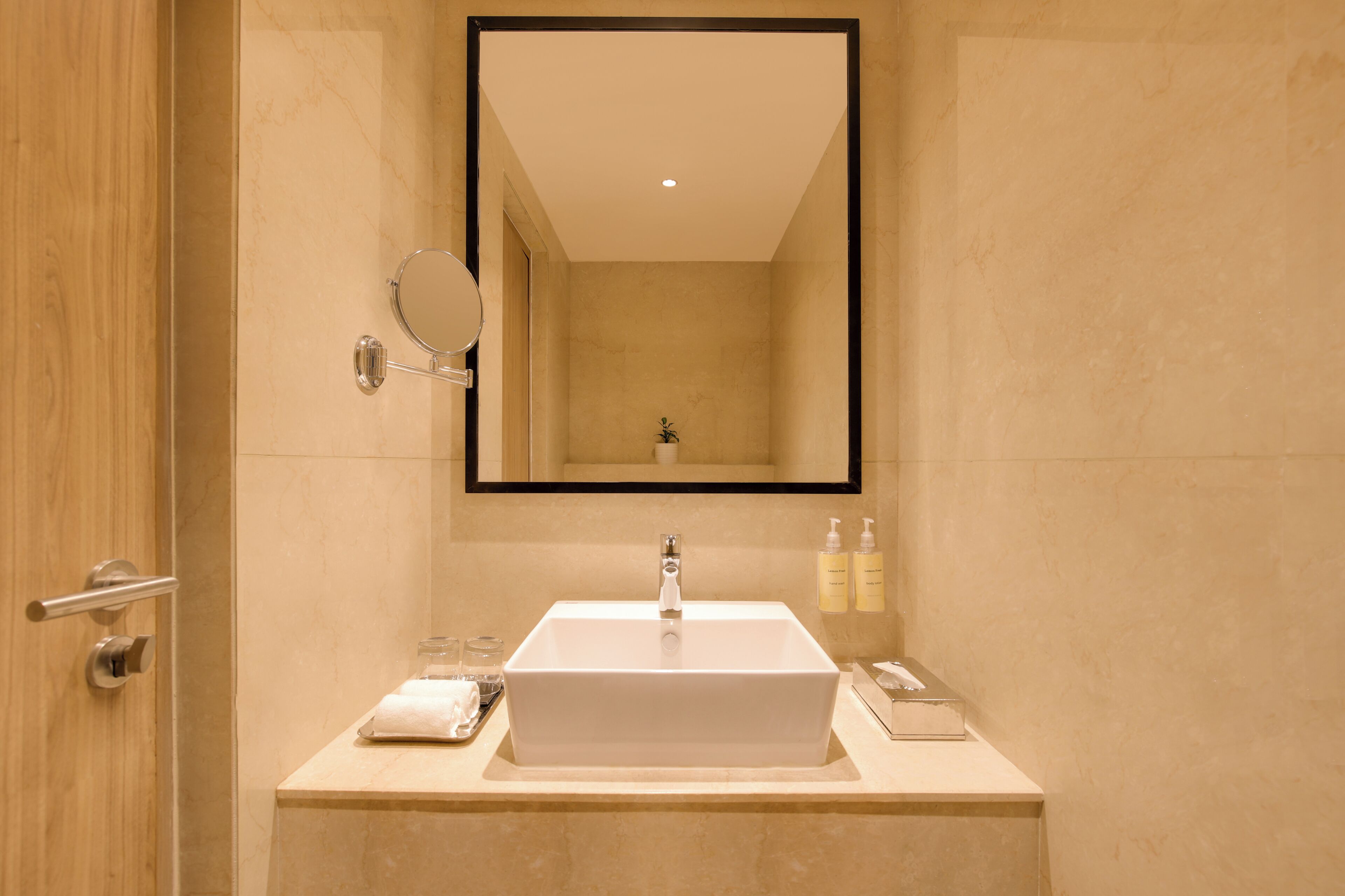 Une salle de bain avec un lavabo blanc, un miroir et deux bouteilles de shampoing posées sur le comptoir.