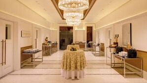 A hotel corridor with a central table set for a meal, flanked by buffet stations and a large chandelier. - Lemon Tree Hotel Bhubaneswar (Bhubaneshwar)