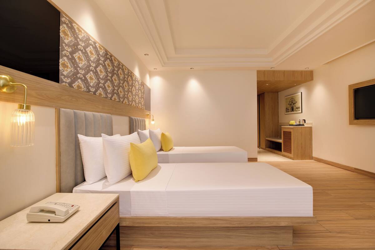 A modern hotel room with a large bed, bedside tables, a desk, and a television.