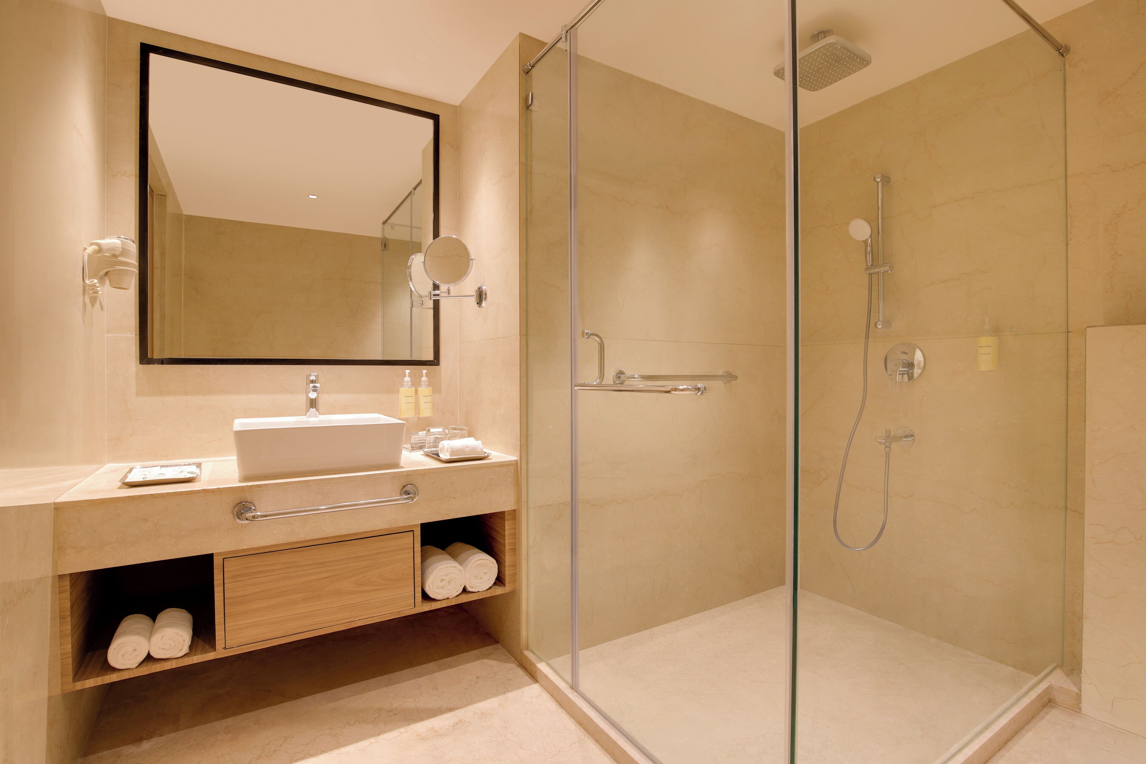Un baño moderno con ducha envuelta en vidrio, un lavamanos con espejo y un tocador de madera con espacio de almacenamiento.