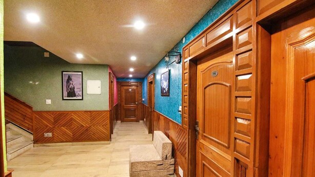 A hallway with wooden doors, a staircase, and a wall-mounted picture. - Hotel City Plaza Dharamshala (Dharamshala)