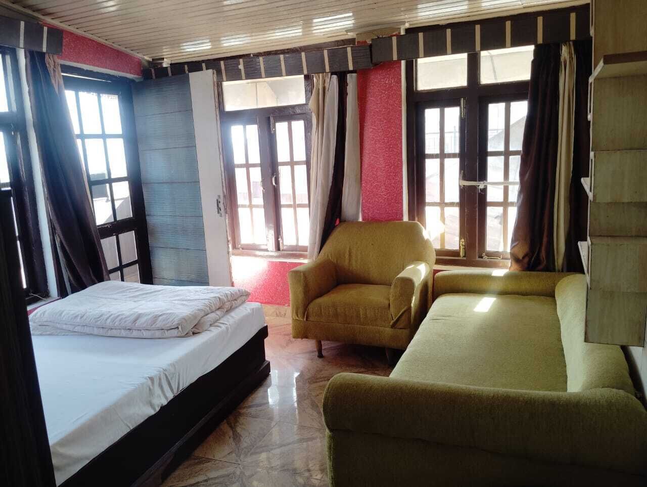 A room with a bed, a sofa, a chair, and a window with curtains.