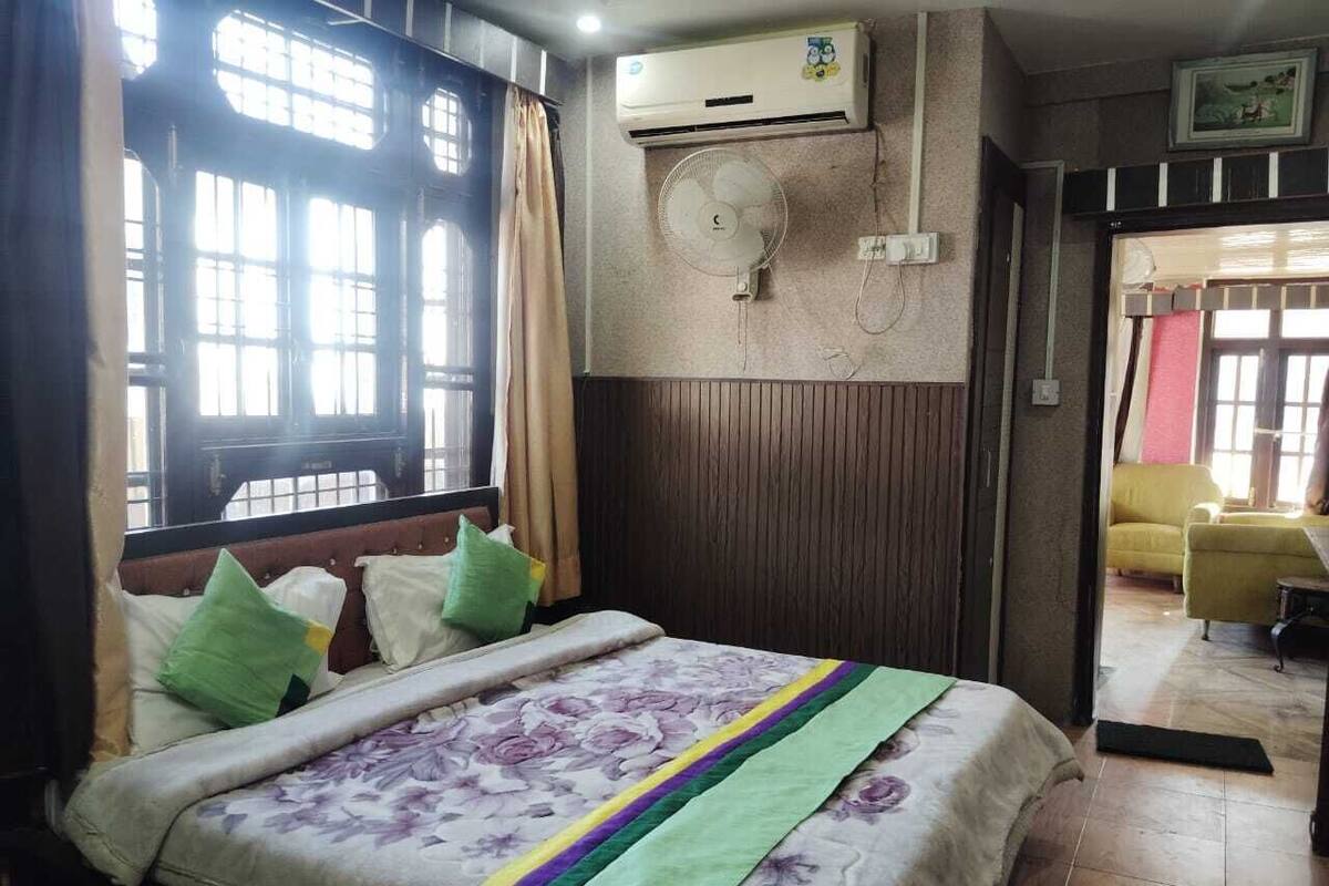 Ein Hotelzimmer mit Bett, Klimaanlage, Ventilator und Blick ins Freie.