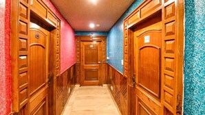 A hallway with wooden doors, each marked with a number. The walls are painted in different colors. - Hotel City Plaza Dharamshala (Dharamshala)