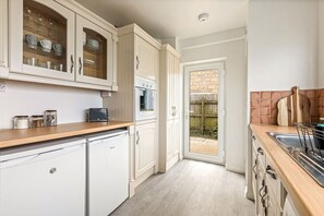 A kitchen with white cabinets, a built-in oven, a microwave, and a wooden countertop. - The Wild Duck in Bourton-On-The-Water (Bourton-on-the-Water)