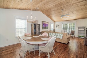 A spacious living area with a wooden ceiling, a dining table with chairs, a sofa, and a fireplace. - TB 71C Carolina Coastal Cozy (Pawleys Island)