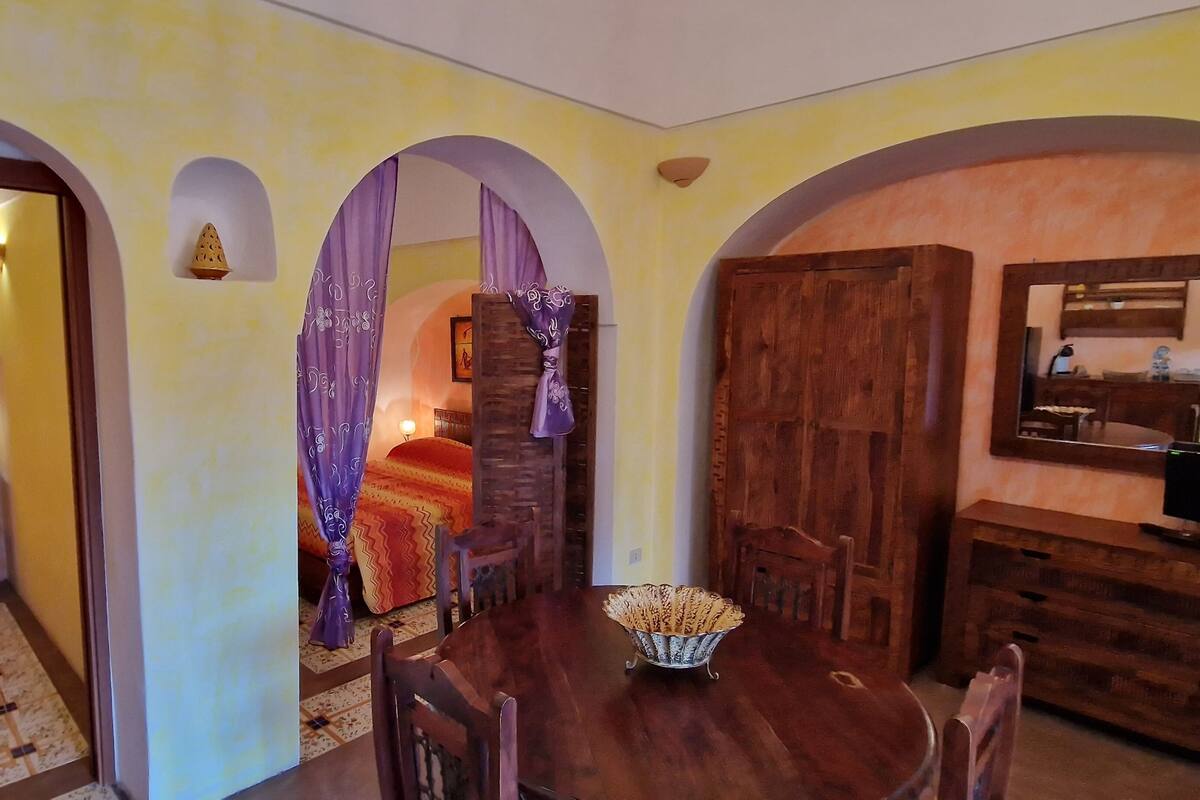 Ein Zimmer mit einem Bett, einem Esstisch mit Stühlen und einem Holzschrank.