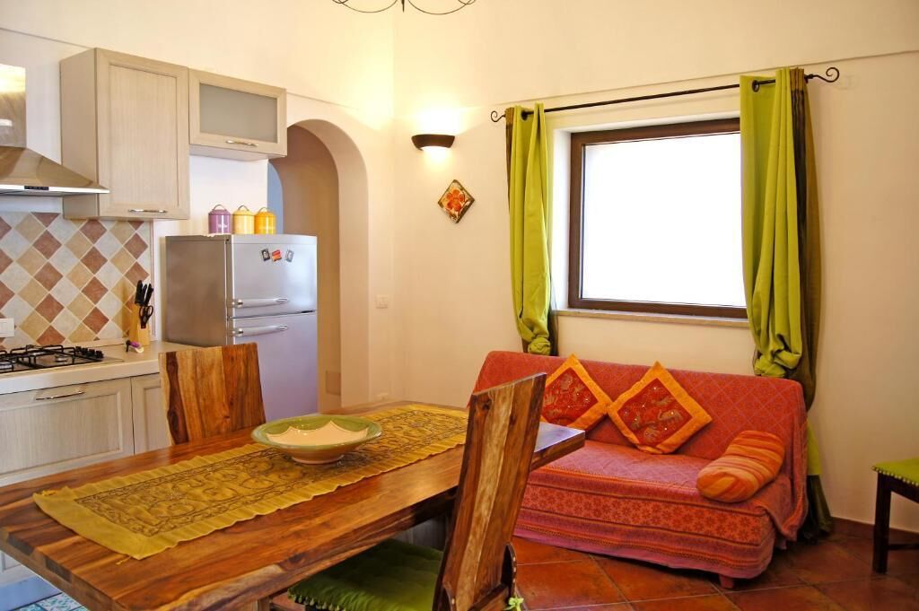 A compact living space with a kitchenette, a dining area, and a sofa with a window view.