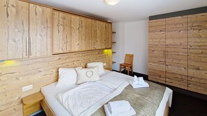 Een slaapkamer met een houten hoofdbord, een bed met witte beddengoed, een stoel en een kledingkast.