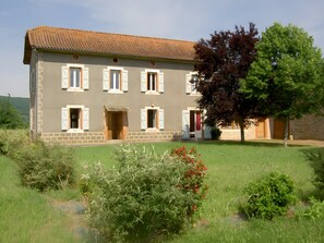 A two-story building with a tiled roof, multiple windows with shutters, and a brick base. - Holiday Home "Maison Au Calme" with Private Terrace and Garden (Féneyrols)