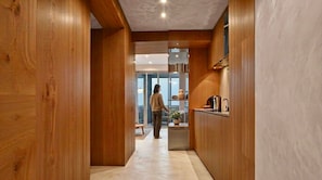 A wooden interior hallway leading to a kitchen area with a person standing in the distance. - Sunny Studio, Balcony & Fast WiFi · 2 min to Beach (Los Cristianos)