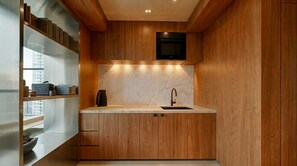 A modern kitchen with wooden cabinetry, a marble countertop, and a built-in oven. - Sunny Studio, Balcony & Fast WiFi · 2 min to Beach (Los Cristianos)