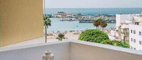 A balcony with a view of a marina, a small round table, and a chair.