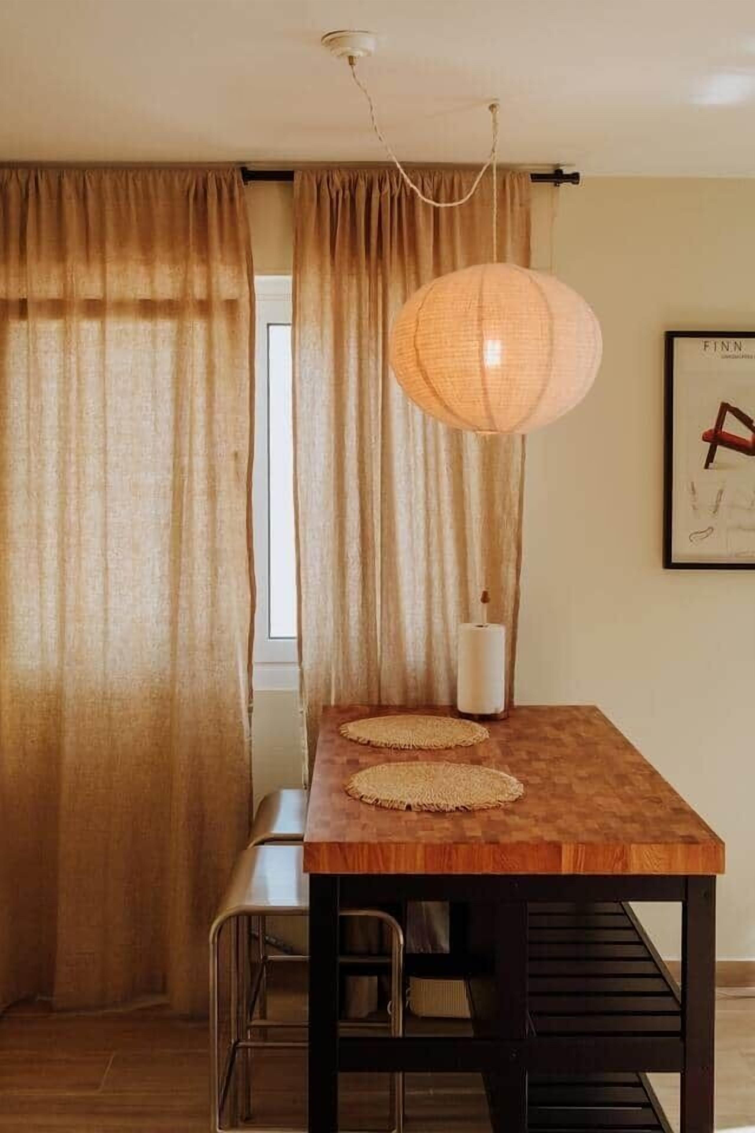 A dining area with a wooden table, a woven placemat, a hanging light fixture, and a framed artwork on the wall.