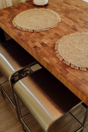 A wooden dining table with two woven placemats and a bench with metal legs. - Stylish Beachside Apt · Terrace · AC · 3 min Beach (Los Cristianos)