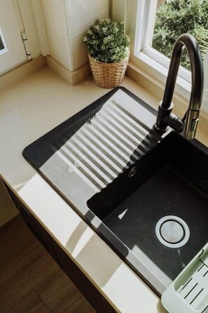 A kitchen with a black sink, a window, and a potted plant. - Stylish Beachside Apt · Terrace · AC · 3 min Beach (Los Cristianos)