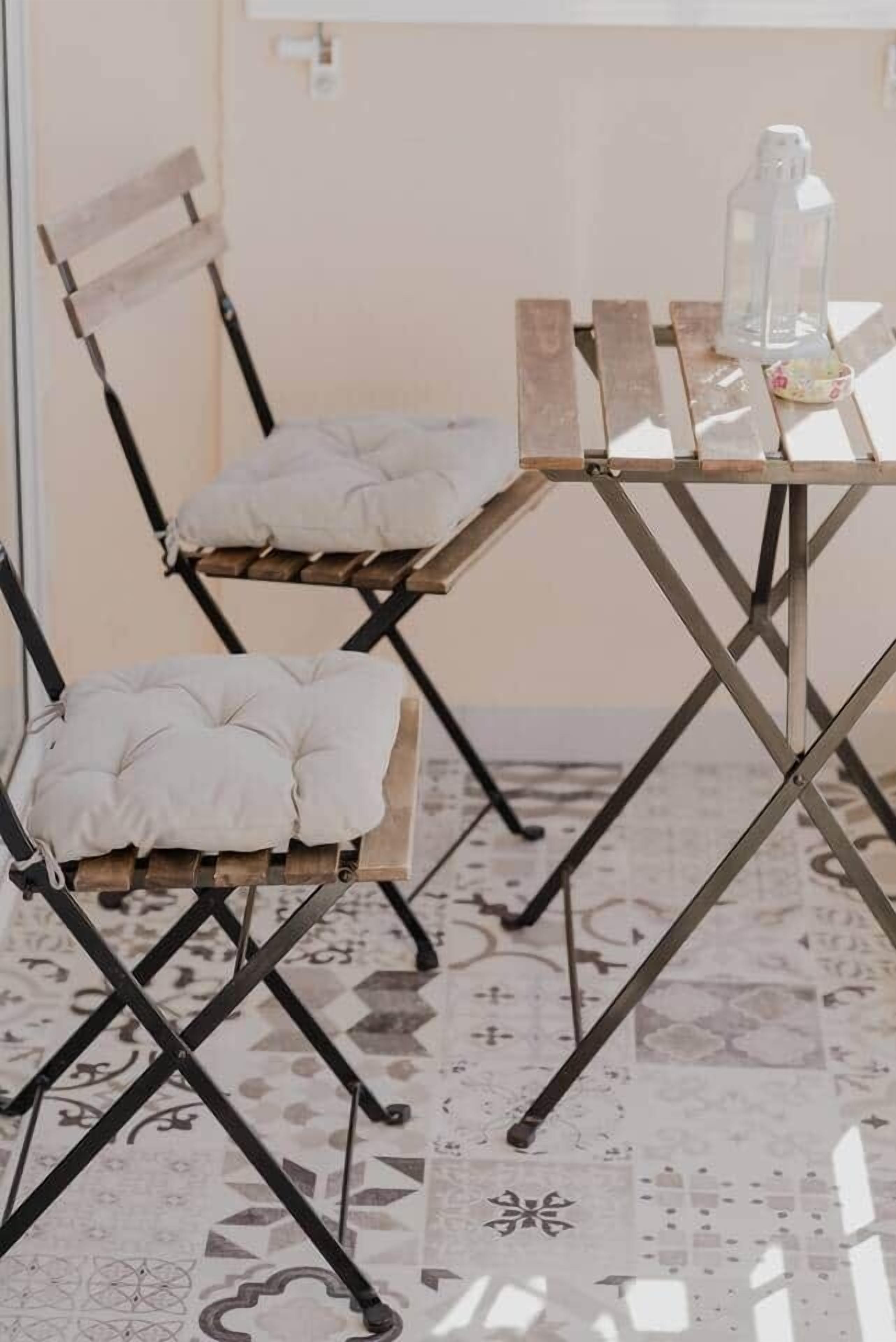 A dining area with a table and two cushioned chairs.