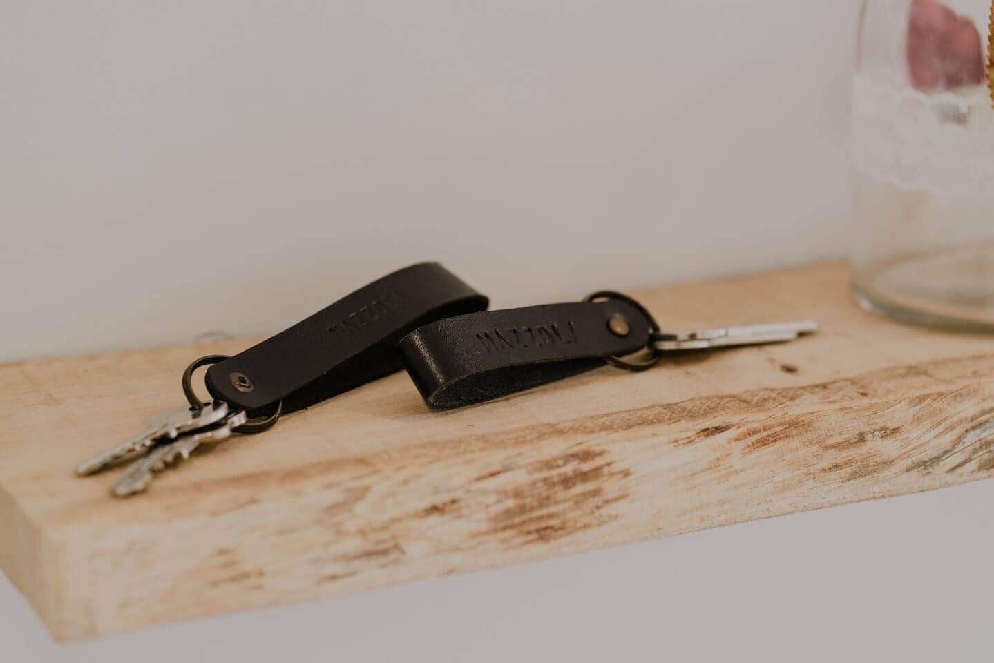 Schlüssel mit Lederband auf einer Holztischplatte.