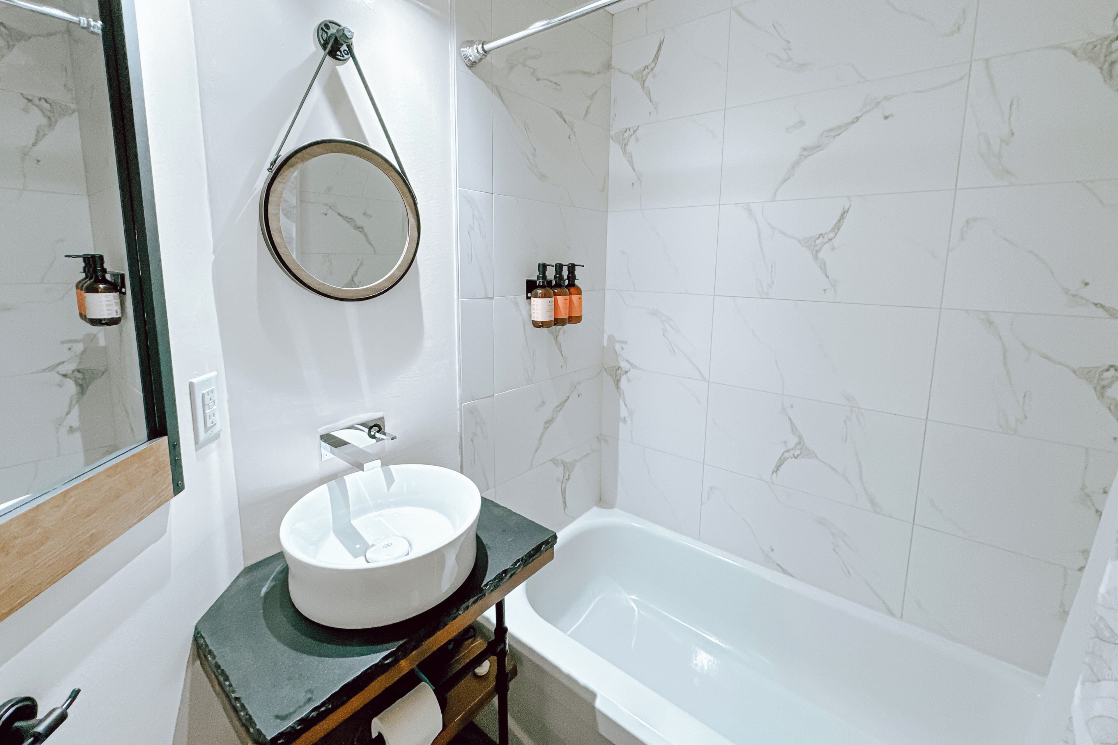 A bathroom with a white sink, a mirror, a towel rack, and a bathtub.