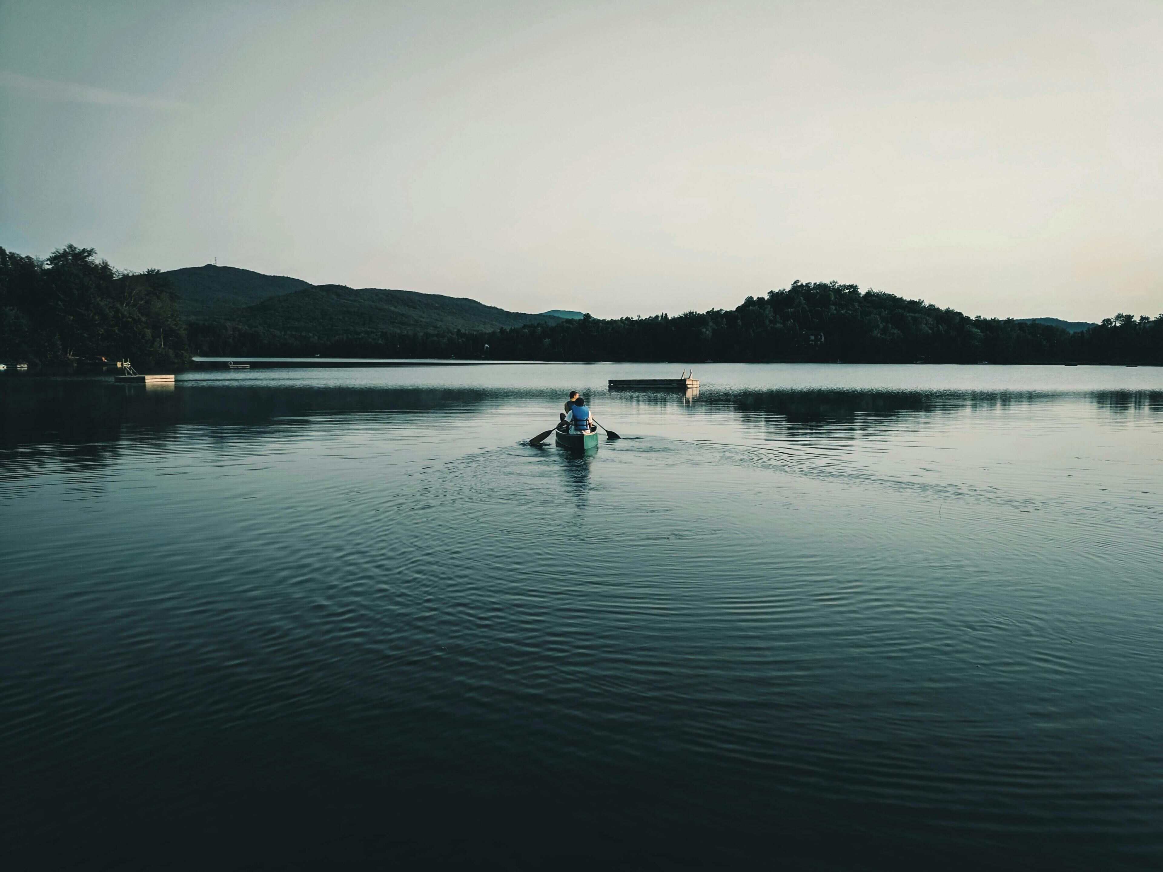 A calm lake with a person rowing a boat.