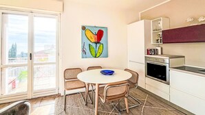 Una cocina con comedor, un cuadro y vistas a través de un ventanal.