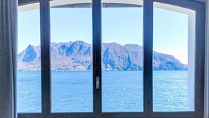 Ein Zimmer mit großem Fenster und Blick auf eine Berglandschaft und ein Gewässer.