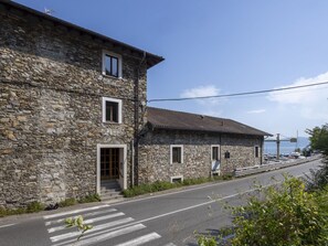 Un edificio in pietra con un attraversamento pedonale, una strada e uno specchio d'acqua sullo sfondo.