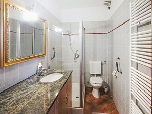 Un bagno con doppio lavandino, toilette, doccia e uno specchio grande.