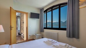 Ein Hotelzimmer mit Bett, Fernseher, Blick auf Berge und Bad.