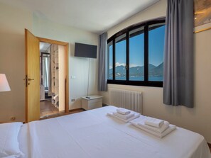Ein Hotelzimmer mit Bett, Fernseher, Blick auf Berge und Bad.