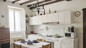 Une cuisine avec des meubles blancs, une cuisinière à gaz, un four à micro-ondes et une table à manger avec des chaises.