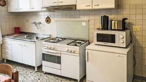 Une cuisine avec des meubles blancs, une cuisinière à gaz, un four à micro-ondes et un petit réfrigérateur.