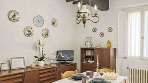 Un coin repas avec une table dressée pour quatre personnes, un meuble en bois, un téléviseur et des éléments de décoration murale.