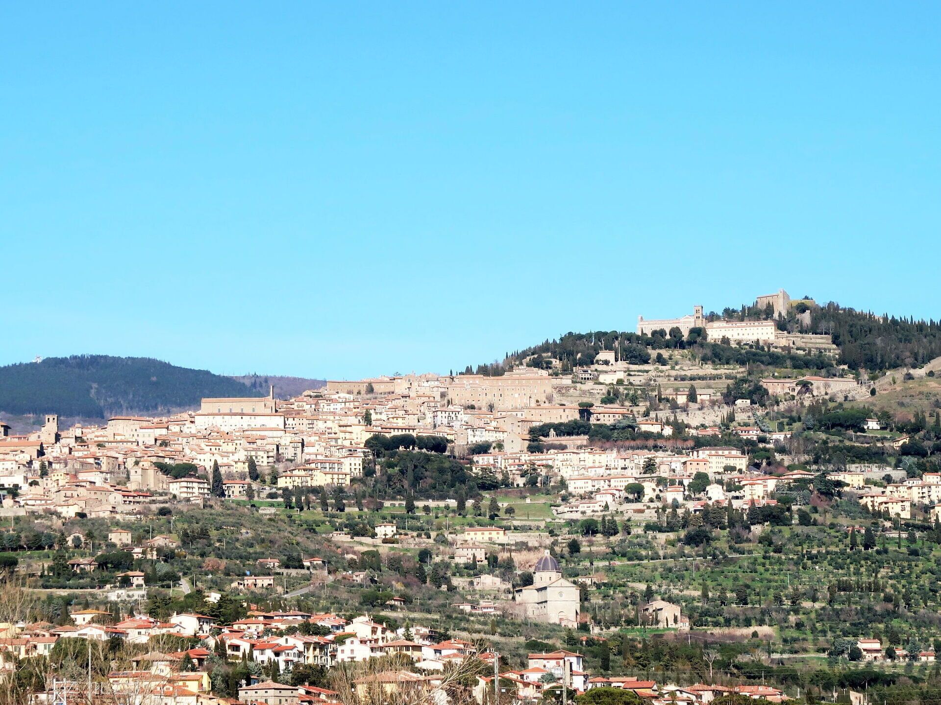 Une vue panoramique d’une ville historique dominée par une imposante forteresse située au sommet d’une colline.