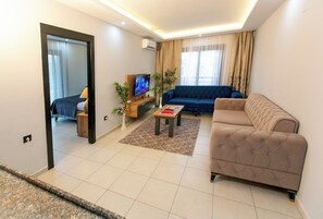 A modern living room with a sofa, a coffee table, and a TV. - LOCA MARİN OTEL (Kocasinan)